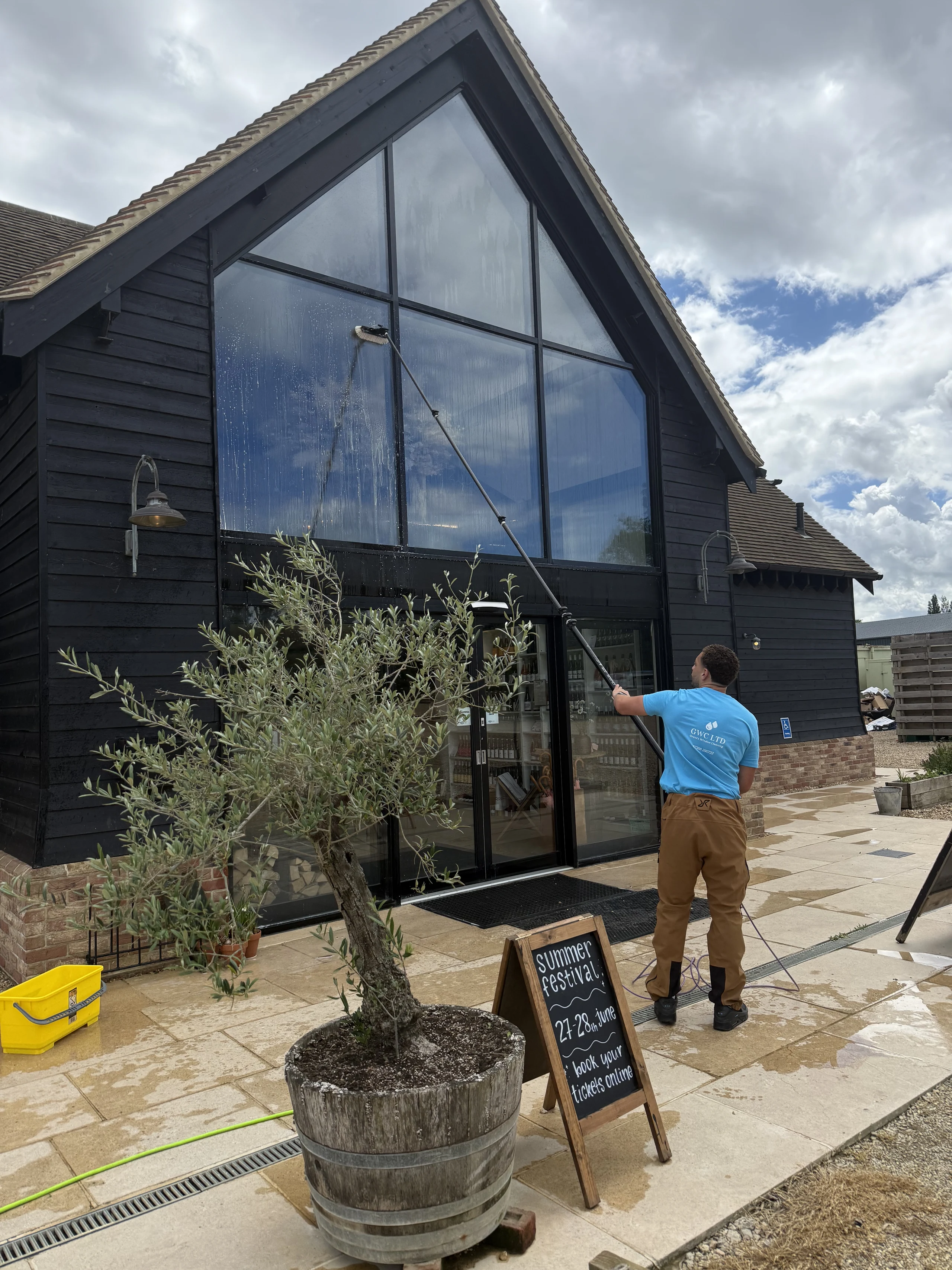GWC LTD operative cleaning the full-height glazed gable of a commercial barn venue with a water-fed pole